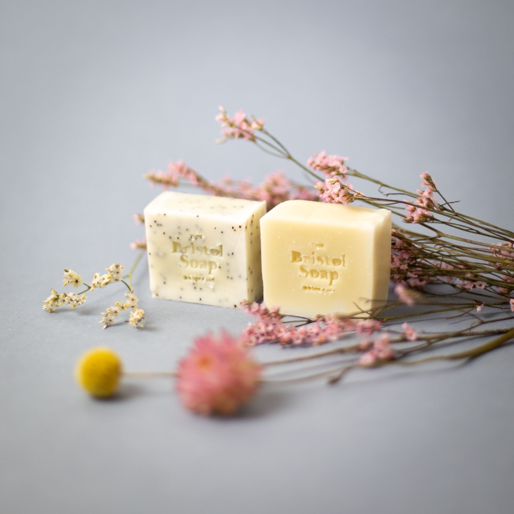 Two hand-made soap blocks by The Bristol Soap Company, with dried flowers in pink and yellow.