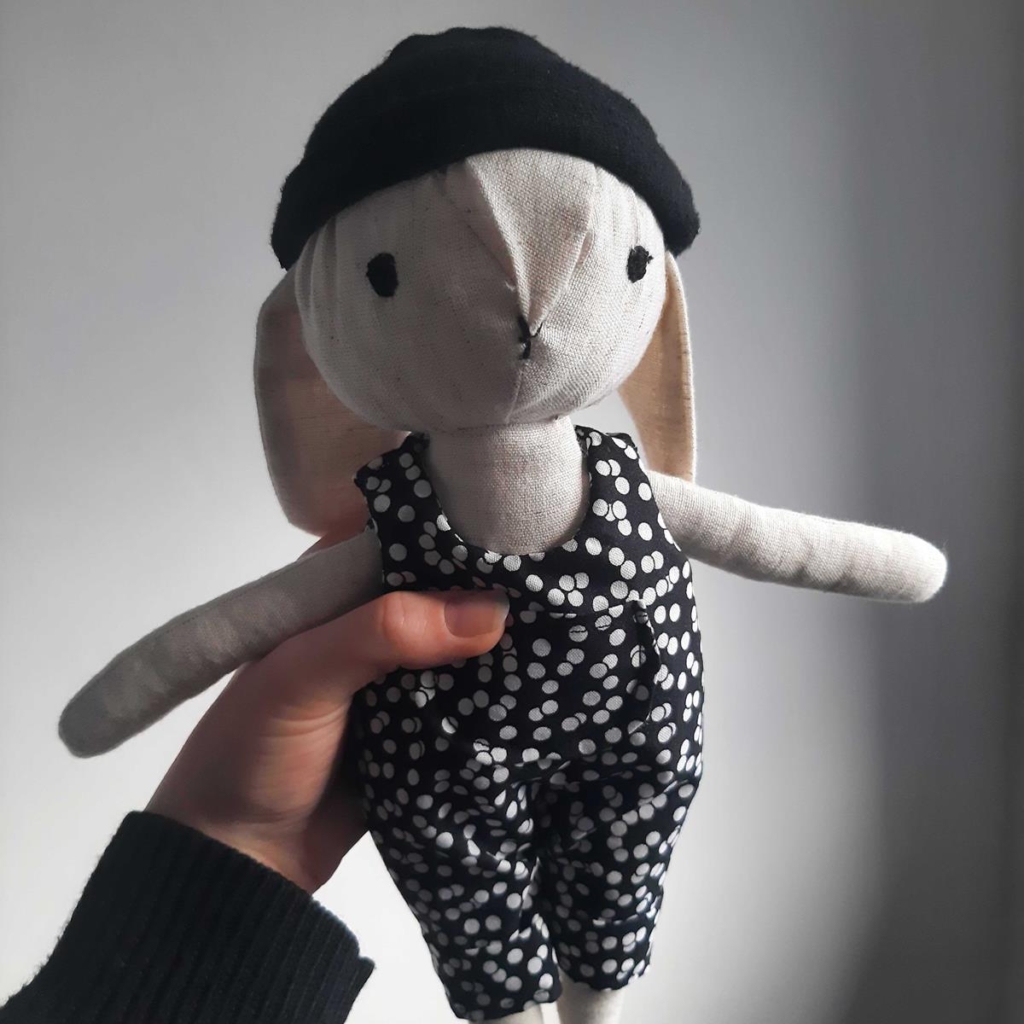 fabric rabbit wearing black hat and black and white spotted dungarees