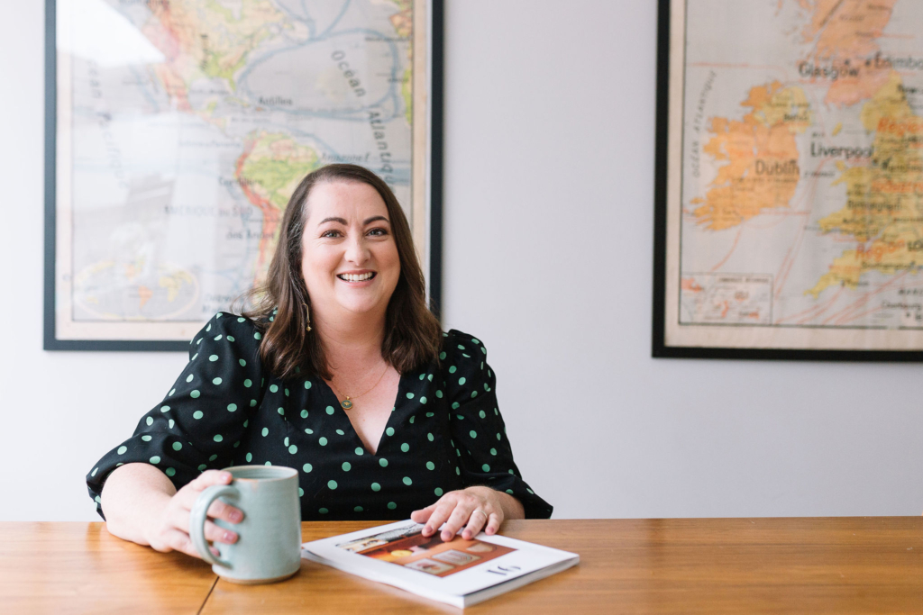 Catherine Erdly sitting at a desk with a coffee cup and magazine.