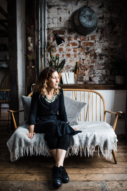 Amelia Twine of Sustainable Fashion Week sitting on an Ercol style settee.