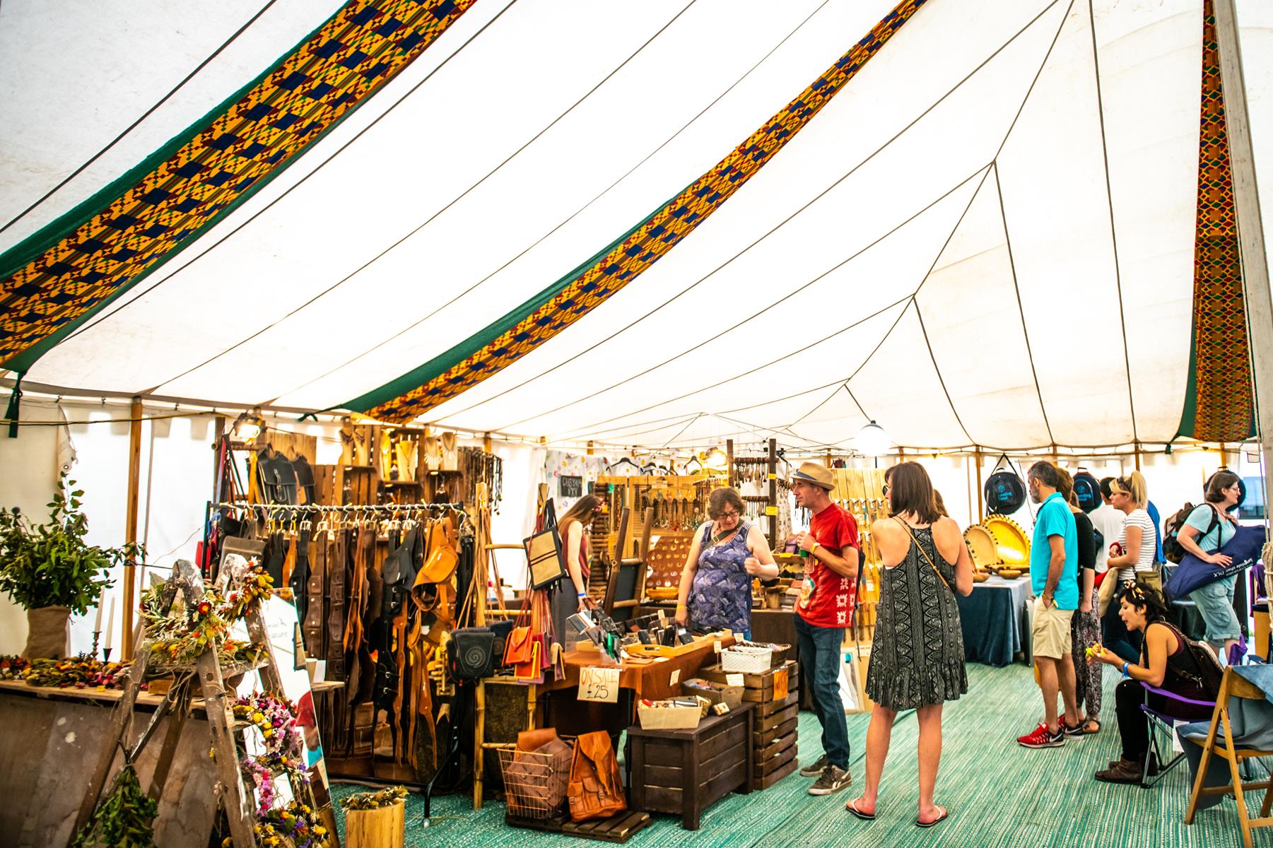 WOMAD Festival - trader stall selling leather goods inside a craft tent.