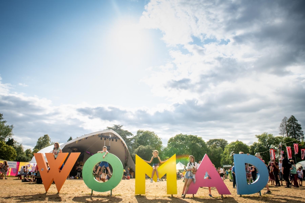 WOMAD Festival - children playing on large brightly coloured letters spelling 'WOMAD'.