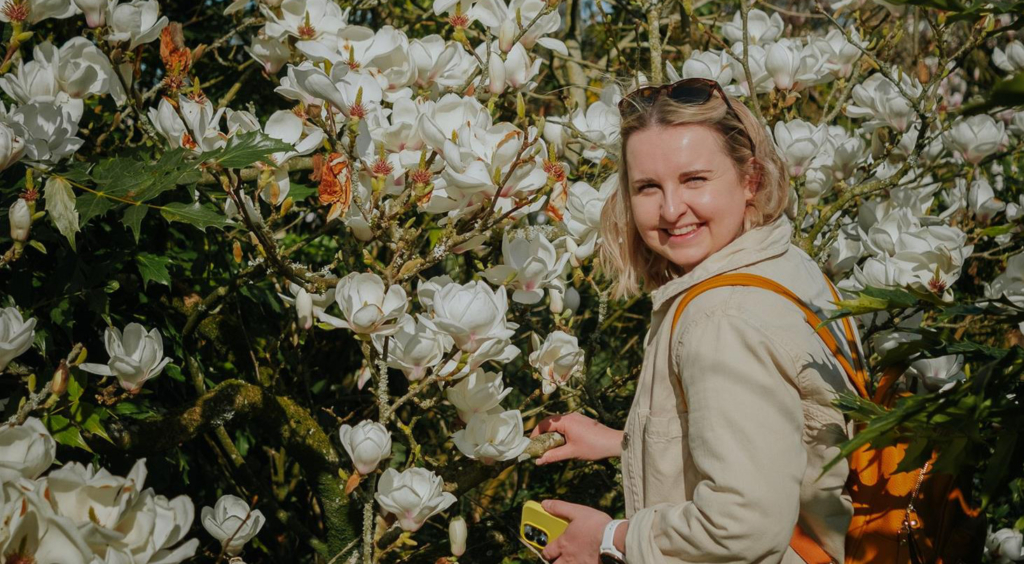 Hannah Isted of HI Communications, an outdoor shot of Hannah by a magnolia bush in full flower..