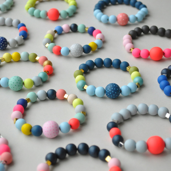 Selection of bracelets made with large round wooden beads in brighly painted beach and ice cream shades. Made of sustainable painted wood, by Sea Pink Studio.