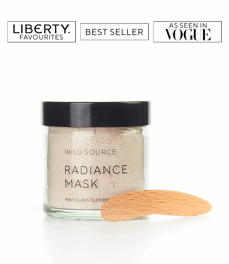 Light coloured powder in a glass jar, with brand name 'Wild Source' and 'Radiance Mask - pink clay and elderberry' written on jar.