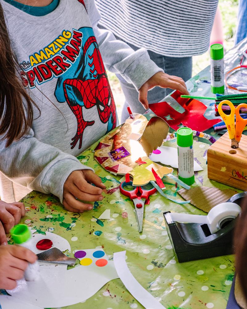 Craft stall with children cutting up and sticking brightly coloured pieces of paper