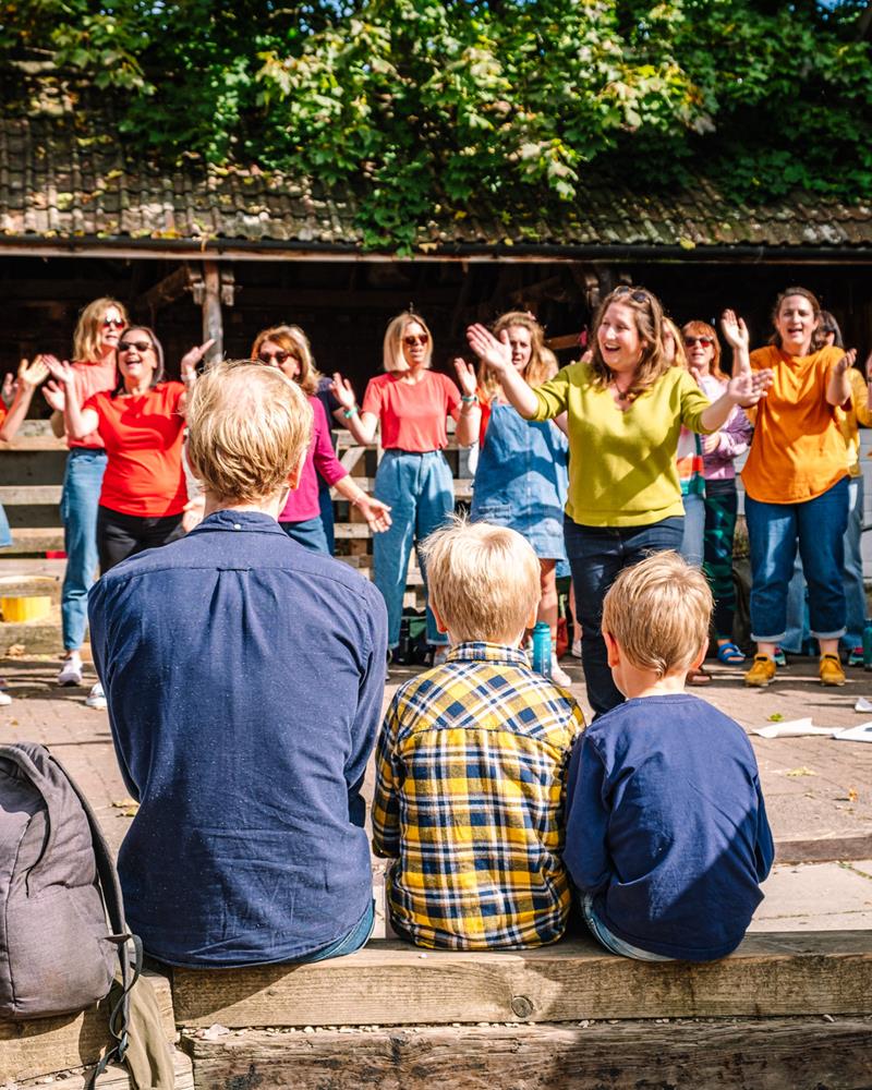 women in brightly coloured tops performing in front of family audience