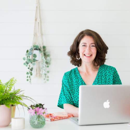 Louisa Chudley of Spark Social sitting at a desk, using an Apple Mac computer and smiling.