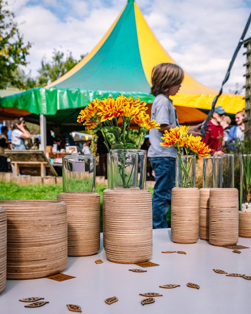 Windmill Hill Market at Windmill Hill Farm. Wooden plant holders on stall in foreground, market in background with brightly coloured tent