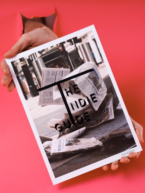 Cover artwork of The Indie Guide, showing newspapers blowing down a street