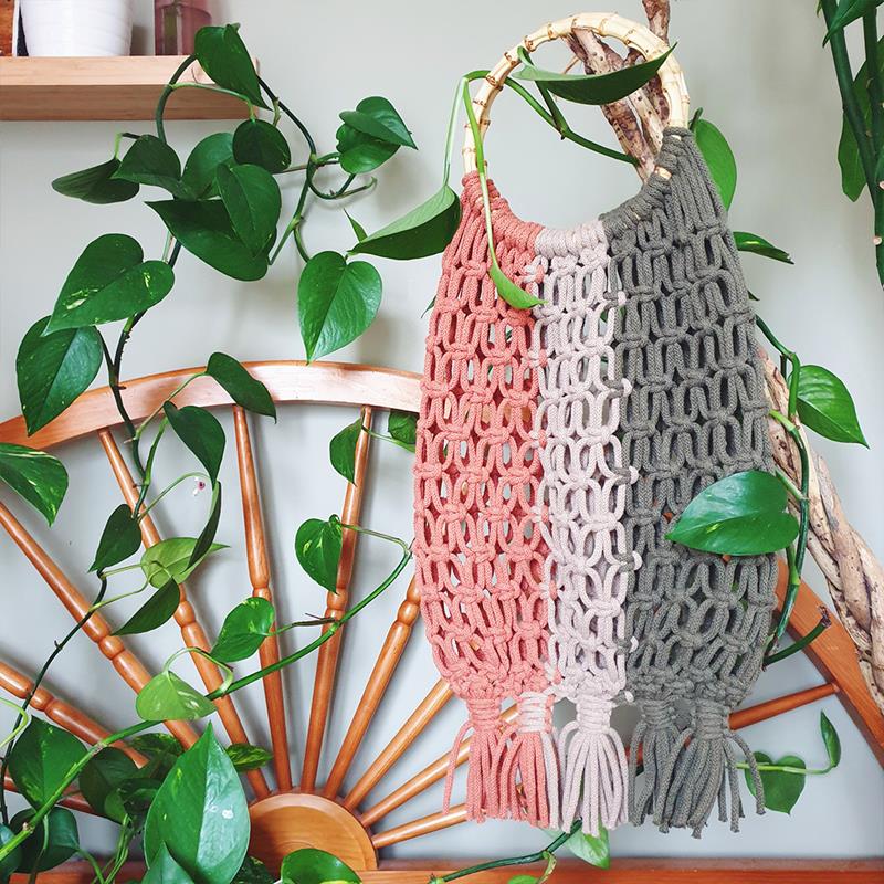 Macrame bag with hooped wooden handle, in three shades - coral pink, pale dusty pink, and grey.