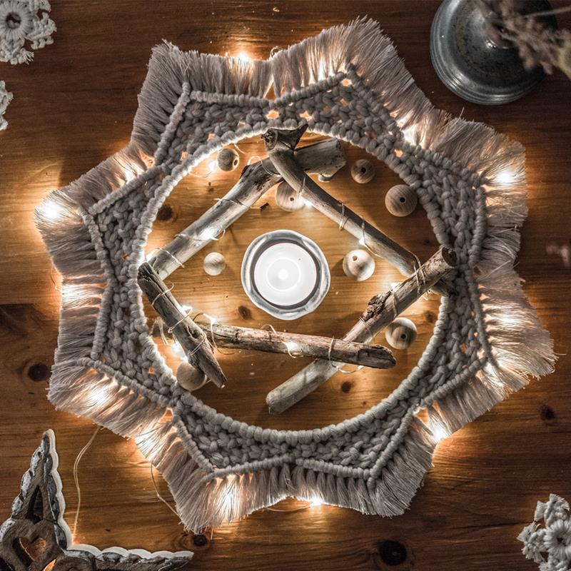Cream coloured macrame Christmas decoration in hooped star shape, with fairy lights behind.