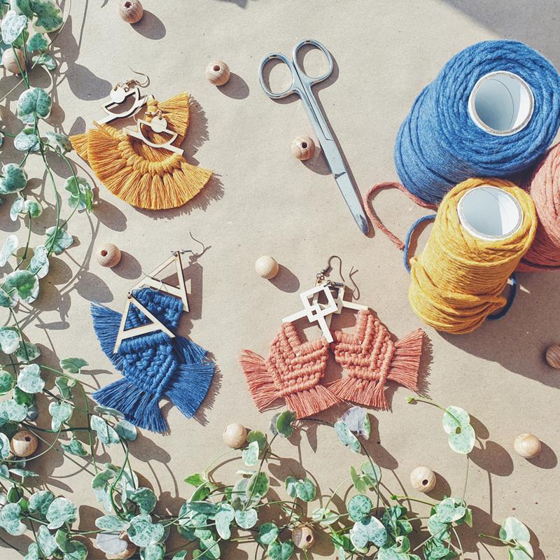 Three sets of macrame earrings, in a fringed design, in mustard, mid blue, and light terracotta.
