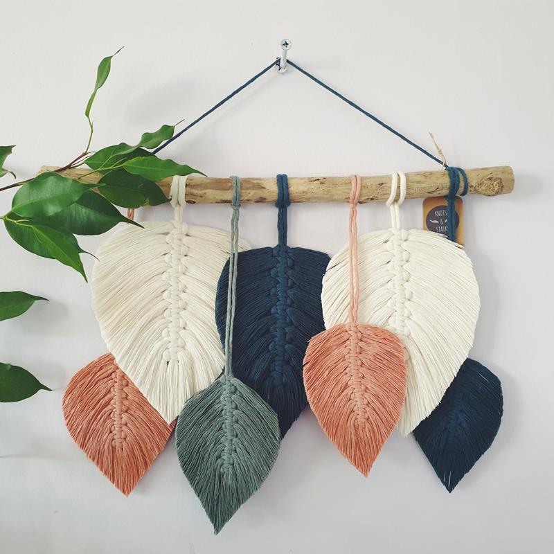 Decorative set of seven leaves, in autumnal shades, hanging from a wooden pole.