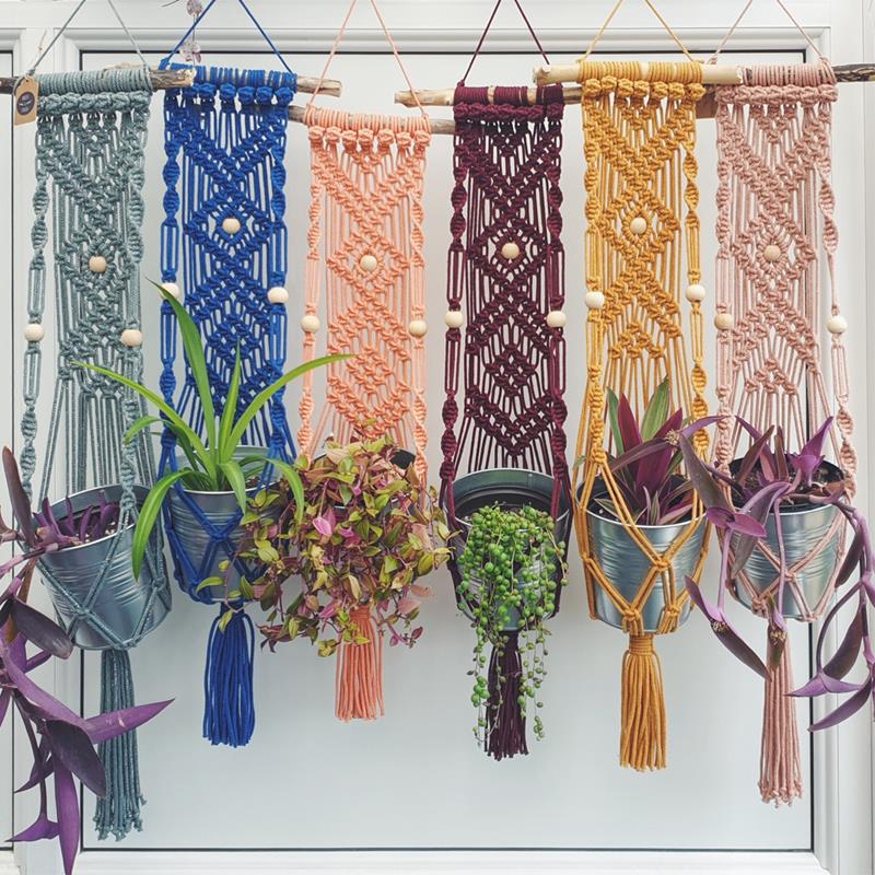 Six macrame plant holders in different colours.