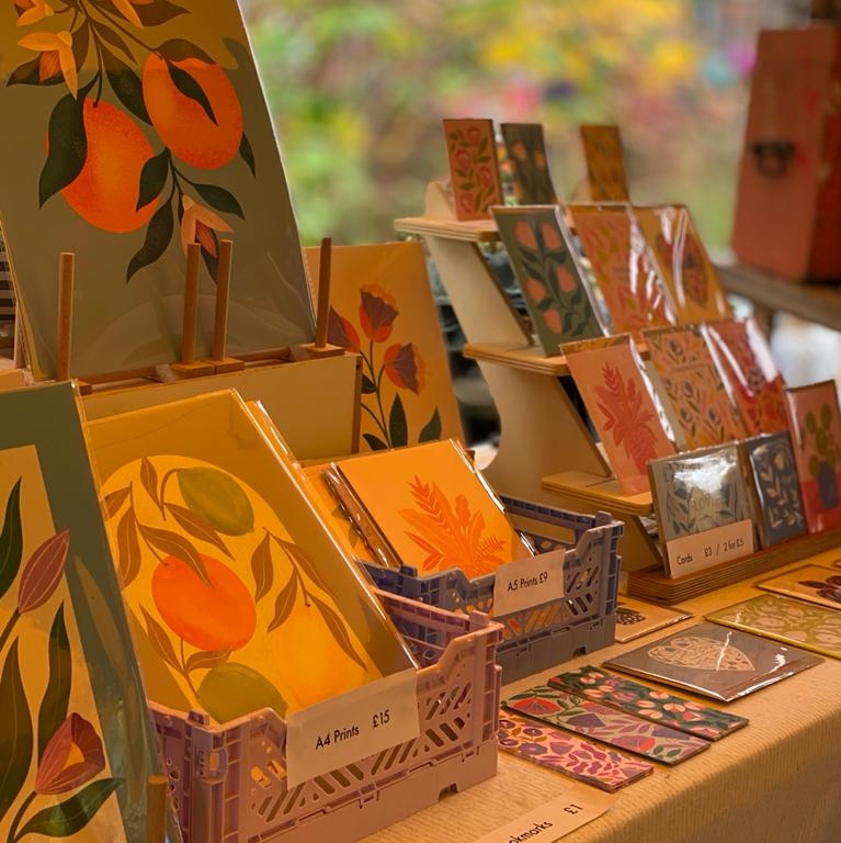 Melissa Donne Studio stall at Windmill Hill Market, displaying colourful prints of fruit and flowers.