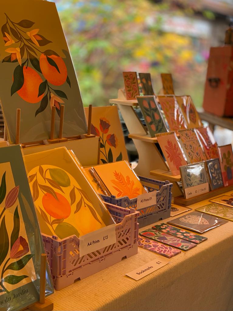 Melissa Donne Studio stall at Windmill Hill Market, displaying colourful prints of fruit and flowers.