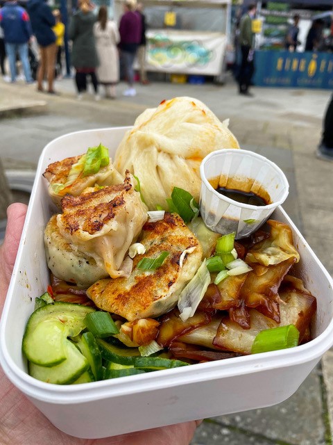 Plate of street food by Ah Ma's Dumplings - a tasty looking variety of dumplings with chopped salad and dark dipping sauce.